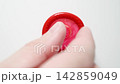 MACRO: Male fingers takes a red condom from a white background - Top view 142859049