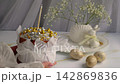 Female Hands presenting an elegant festive Easters cupcake topped with shimmering gold and silver sugar pearls and a candle 142869836