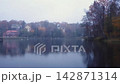 View from embankment of city pond on calm mirror water surface and European style residential buildings on waterfront among autumnal foliage trees at rainy dusk. Late autumn tranquil misty landscape. 142871314