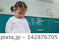 A little Caucasian girl stands in a room and looks around with curiosity. The scene represents Montessori education, independent exploration, early childhood development 142876705
