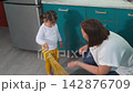 Young educator and little girl clean together in a kindergarten classroom while practicing sweeping. The activity represents Montessori learning, practical skills, concentration, and independence. Top 142876709