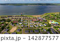Wide horizontal aerial drone video of Ruiterplaat holiday park, modern bungalows, solar roofs, water slide, marina jetty, and Veerse Meer lake in Kamperland, Zeeland, Netherlands on sunny day 142877577