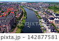 Wide horizontal aerial drone video of residential canal district, modern waterfront houses, small motorboats cruising, solar roof panels, and green park paths in Leiden, South Holland, Netherlands 142877581