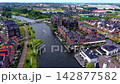 Wide horizontal aerial drone video of Leiden residential canal, modern waterfront apartments, small motorboats, pedestrian bicycle bridge, and green park paths in South Holland, Netherlands 142877582