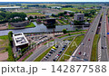 Wide horizontal aerial drone video of multi-lane highway overpass, canal waterway, McDonald's restaurant, office buildings, parking lots, and polder landscape in Leiden, South Holland, Netherlands 142877588