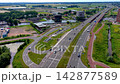 Wide horizontal aerial drone video of multi-lane highway bridge over canal, traffic intersection, bicycle paths, office buildings, and green landscape in Leiden, South Holland, Netherlands 142877589