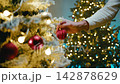Hand Decorating Snowy Christmas Tree With Red Bauble 142878629
