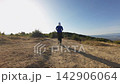 Trail running woman jogging mountain hillside with determined focus and natural light 142906064