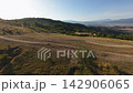 Aerial landscape drone view of rolling agricultural fields and forested foothills at golden hour 142906065
