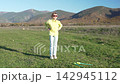 Exercise stretching mountains. Young girl practices fitness routine outdoors in a beautiful sunny green mountain valley. 142945112