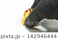 Chef wearing black gloves picks up a fresh coconut macaroon on a seamless white background. Ideal for bakery ads and food business promos. 142946444
