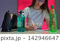 Focused young woman with glasses writing on document at desk 142946647