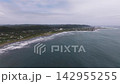 夏の曇り空、千葉県の弓なりの砂浜と打ち寄せる白波、沿岸の集落を望むドローン空撮 142955255