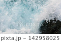 Waves crashing over rugged black volcanic rocks, creating white foam, splashes, and flowing seawater. Slow motion 142958025