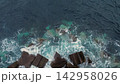 Aerial view of powerful ocean waves crashing against concrete breakwater blocks on the Madeira coast. 142958026
