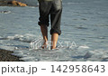 Barefoot walking beach person strolls on pebble shoreline enjoying calm ocean waves 142958643