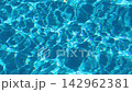 Abstract blue swimming pool water surface with gentle ripples, shimmering sunlight reflections, and moving wave patterns. 142962381