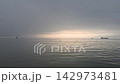 浩瀚的海洋籠罩在晨霧之中，遠處一艘船的輪廓清晰可見；晨光從地平線傾瀉而下，海面平靜而波光粼粼。 142973481