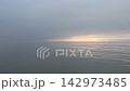 一張寧靜的海洋景觀背景圖片，展現了波光粼粼的水面和穿透遠處雲層的光線，非常適合冥想、瑜伽或作為背景音樂。 142973485