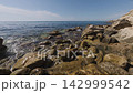 Enjoying the Costa Blanca coastline and rocky shore in Benidorm at midday with clear skies and calm waters 142999542