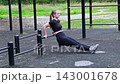 Sporty woman doing triceps dips on parallel bars at an outdoor gym, arm muscle training, fit body, active daily routine 143001678