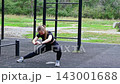 Sporty woman doing pre-workout warm-up on an outdoor sports field, stretching muscles, injury prevention, active daily routine 143001688
