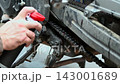 Close-up view of motorcycle chain service, applying lubricant to the drive chain, hands, mechanical repair and upkeep 143001689