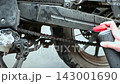 Close-up view of motorcycle chain service, applying lubricant to the drive chain, hands, mechanical repair and upkeep 143001690