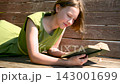 Teenage schoolgirl studying reading her books, lying down outdoors. 143001699