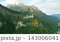 Experience the beauty of Neuschwanstein Castle, nestled among lush mountains in Bavaria. The early morning sun highlights its stunning architecture and scenic surroundings. 143006041