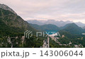 Neuschwanstein Castle stands majestically surrounded by lush forests and mountains. This early morning captures its enchanting beauty, showcasing the serene landscape of Bavaria, Germany. 143006044