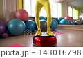 Fitness enthusiast performs balance exercises in a gym setting with colorful equipment 143016798