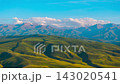 drone hyperlapse above rolling green hills and snowcapped mountains at the horizon 143020541