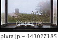 A table with books and a candle, a view of a tranquil forest through the window, and an atmospheric, peaceful hillside path shrouded in mist. 143027185