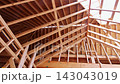 Workers are building roof structure using wooden beams for construction in progress 143043019