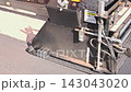 Large paving machine works on road, laying down fresh asphalt at construction site 143043020