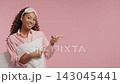 Smiling homy teen girl presenting an empty pink right side space. Young young woman recommending 143045441