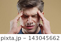 Handsome man feeling severe headache, beige studio background. Hands on head, facial expression of 143045662