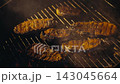 Whole Sea Trout Grilling on Barbecue Rack Outdoors During Evening Dinner. Appetizing seafood 143045664