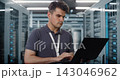 Network Engineer Configuring Server Racks with Laptop in Data Center 143046962