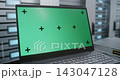 Laptop with Green Screen Display on Table Beside Server Racks in Data Center 143047128
