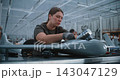 High Tech Defense Industry Worker Integrating Payload into Reconnaissance Drone 143047129