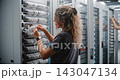 Female Network Engineer Connecting Ethernet Patch Cables in Data Center 143047134