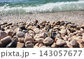 Pebbles on the beach with ocean waves in the background on a sunny day 143057677
