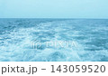 White foamy wake left by a boat on the turquoise blue ocean surface under a clear sky. Wide seascape featuring bubbles, splashes, and ripples in the water. Beautiful maritime background with horizon. 143059520