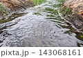 Water Rippling Over Mossy Rocky Bank in Calm Lake 143068161