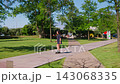 A Serene Stroll through Lush Greenery: Discovering Nature and Architecture Along a Scenic Park Pathway in Bright Sunshine 143068335