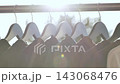 Clothes hanging on a rail with natural light creating a bright and airy atmosphere 143068476