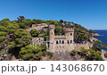 Aerial view of the coastline of Lloret de Mar, Costa Brava, Spain, filmed with a drone - the sea, beach, and castle on the coastal cliffs of the city bay on a sunny day 143068670