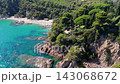 An aerial view of a drone flies over the beach, sea and coastal cliffs near Santa Clotilde Park on a sunny day in the tourist town of Lloret de Mar, Catalonia, Spain 143068672